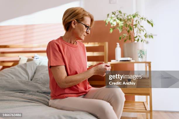 woman preparing to put on an adhesive patch for hormone replacement therapy - oestrogen stock pictures, royalty-free photos & images