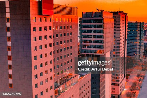 Barcelona skyline from above with dramatic sunset golden light between modern skyscrapers.