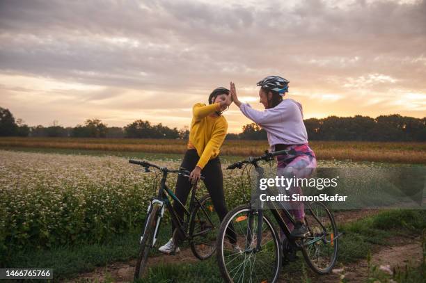 atletas chocando los cinco mientras andan en bicicleta por un camino de tierra - choque de manos en el aire fotografías e imágenes de stock