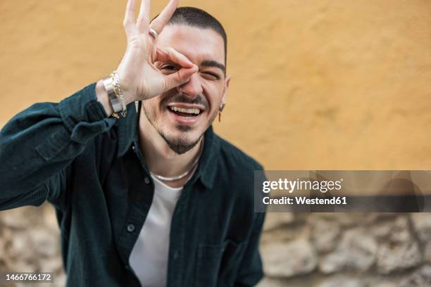 smiling man making ok gesture in front of wall - geste de la main photos et images de collection