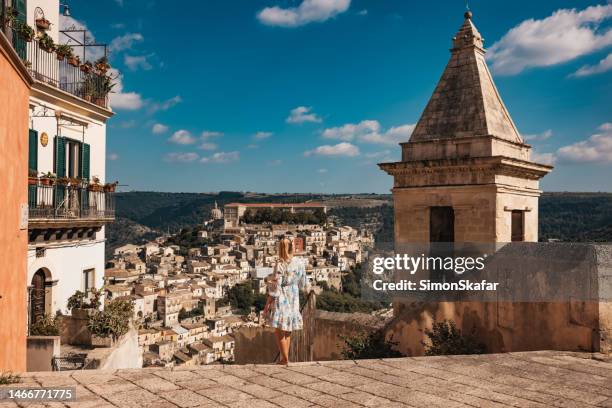 tourist walking on footpath by bell tower on sunny day - sicily stock pictures, royalty-free photos & images