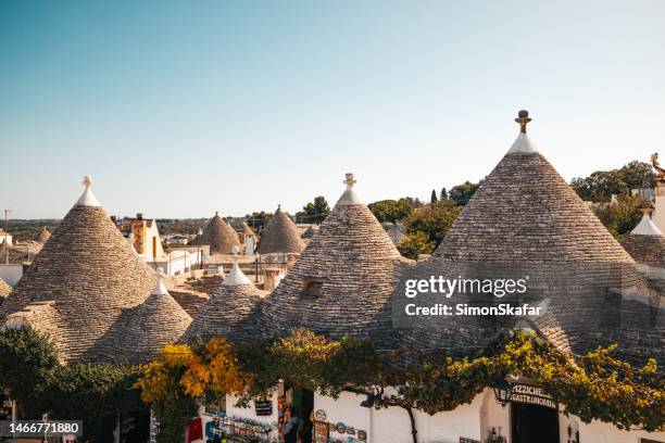 high angle view of trulli houses with conical roofs in a row in old town against clear sky during sunny day at alberobello - puglia italy stock pictures, royalty-free photos & images