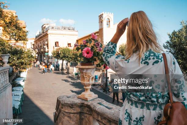 tourist standing by flowering plant in front of church during vacation - taormina stock pictures, royalty-free photos & images