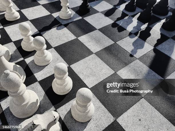 giant chess game on checkered blocks in public park - tablero de ajedrez fotografías e imágenes de stock