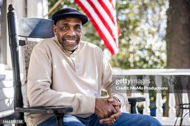 senior man in rocking chair on front porch - amerikanische südstaaten flagge stock-fotos und bilder