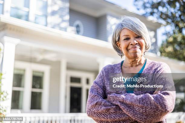 portrait of senior woman in front of suburban home - ageing population stock-fotos und bilder