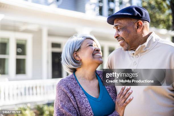 portrait of senior couple in front of suburban home - tシャツ　キャップ ストックフォトと画像