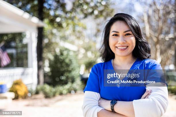 portrait of nurse in front of suburban home - district nurse stock pictures, royalty-free photos & images