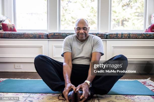 senior man stretching at home - senior yoga stock pictures, royalty-free photos & images