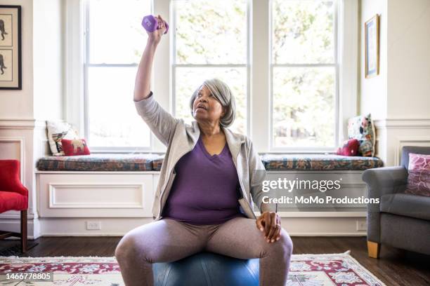 senior woman exercising at home - yoga chair stockfoto's en -beelden