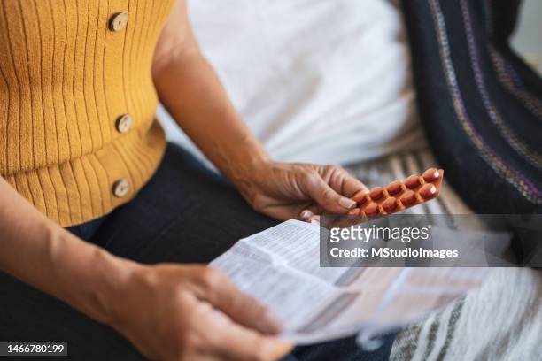 close up of a woman checking patient information leaflet for her medicine. - transdermal stock pictures, royalty-free photos & images