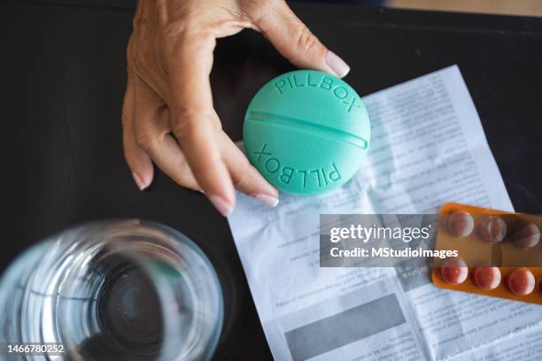 mujer latina sosteniendo pastillero sosteniendo un pastillero - progesterone fotografías e imágenes de stock