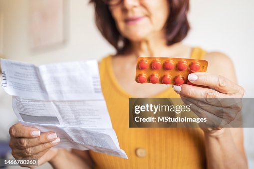 Close up of a woman checking patient information leaflet for her medicine. Close up of a woman checking patient information leaflet for her medicine.
