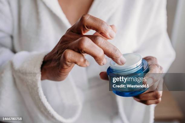 hands of woman with moisturizer in bathroom at home - face cream stock pictures, royalty-free photos & images
