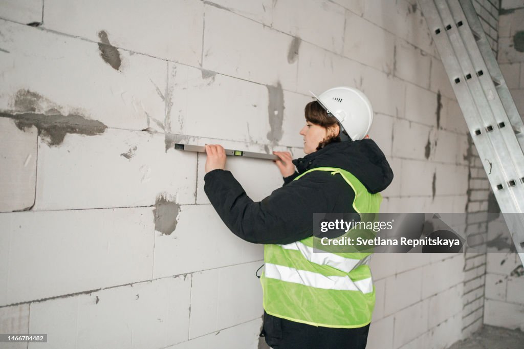Builders Using Measure Female Builder With A Level Measures The Wall Of The House High-Res ...