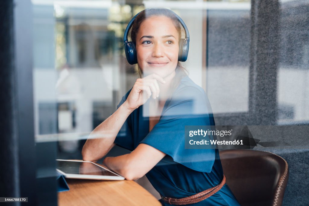 Thoughtful businesswoman wearing headset in soundproof cabin