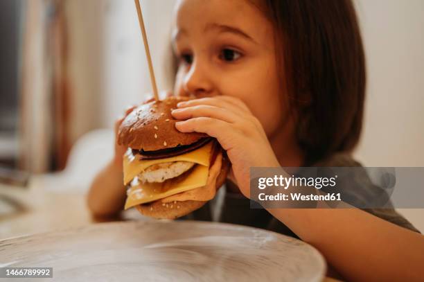 boy eating burger at home - toddler eating sandwich stock-fotos und bilder