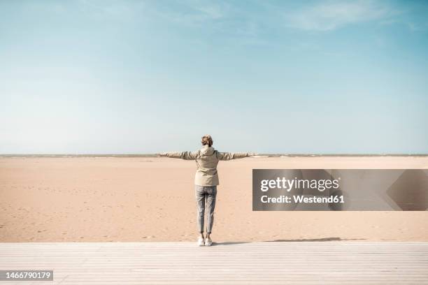 woman standing with arms outstretched on beach - ouistreham stock pictures, royalty-free photos & images