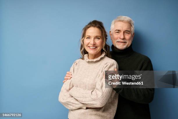 happy mature couple standing together against blue background - smiling woman on gray background 50 stock pictures, royalty-free photos & images