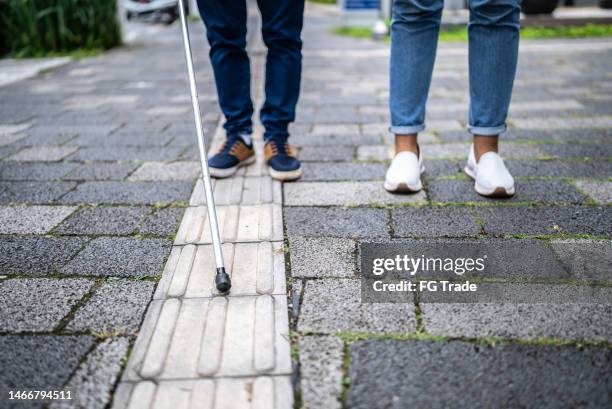 low section of visually impaired person walking in the street - blind man stockfoto's en -beelden