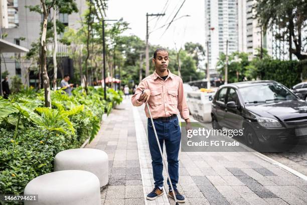 visually impaired man walking in the street with his walking cane - blind man stock pictures, royalty-free photos & images