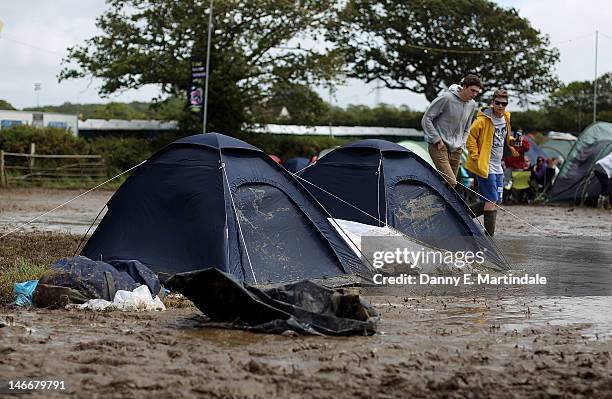 Festival-goers walk past tents on a campsite covered in mud at the Isle Of Wight Festival at Seaclose Park on June 22, 2012 in Newport, Isle of Wight.