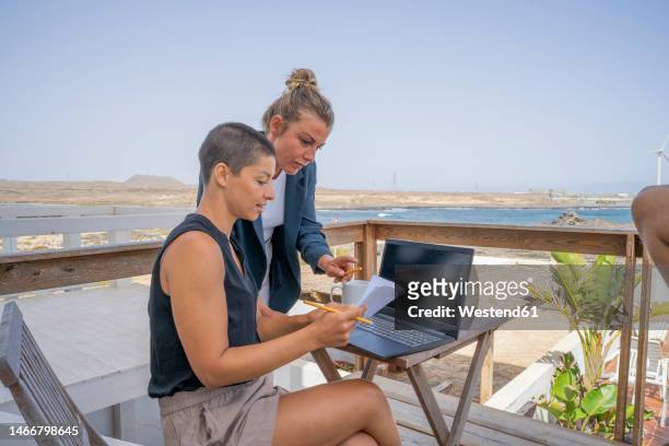 businesswoman assisting colleague holding book on balcony - doing a favor - fotografias e filmes do acervo