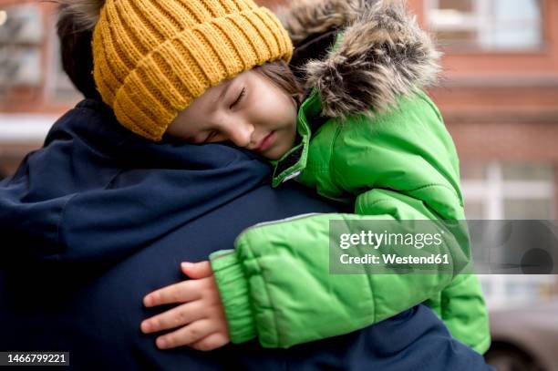tired boy wearing knit hat sleeping on father's shoulder - man sleeping with cap stock pictures, royalty-free photos & images