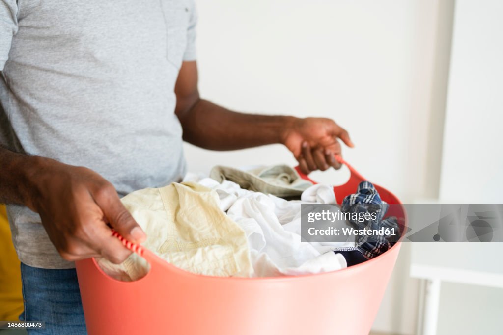 Man holding laundry basket at home