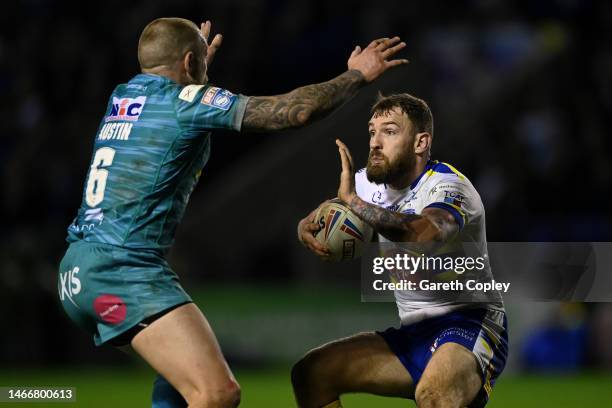 Daryl Clark of Warrington hands off Blake Austin of Leeds during the Betfred Super League between Warrington Wolves and Leeds Rhinos at The Halliwell...