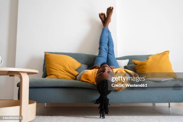 man lying upside down on sofa at home - man upside down stock pictures, royalty-free photos & images