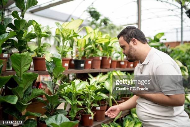 young special needs man working using digital tablet in a garden center - botany downs stock pictures, royalty-free photos & images