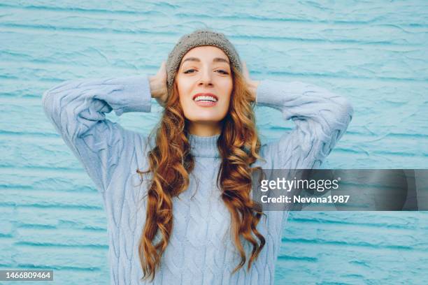 ritratto di donna sorridente che porta cappello e maglione blu su priorità bassa blu - woman face hat foto e immagini stock