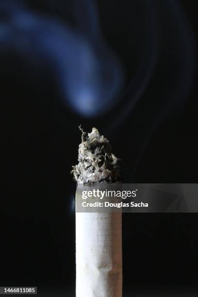 burning and smoking cigarette on a black background - kautabak stock-fotos und bilder