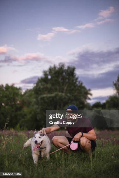 junger mann tätschelt seinen husky-hund in der natur - dog drinking stock-fotos und bilder