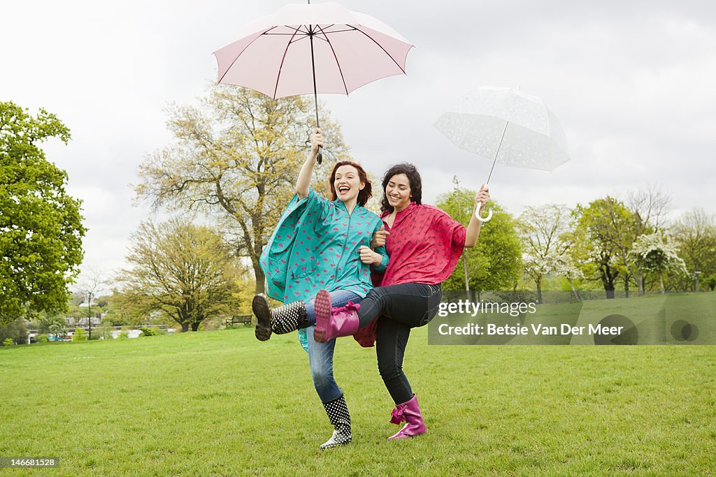 Young women dancing in rain, holding umbrella's.