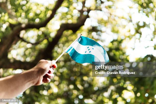 hand holding a small honduras flag in  the sky. - honduras stock pictures, royalty-free photos & images