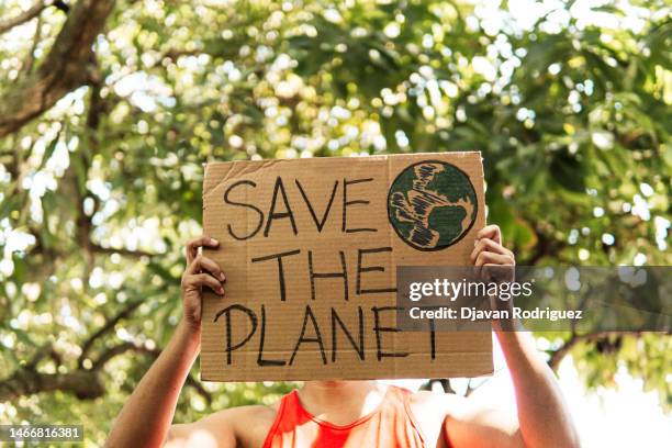 a person holding a "save the planet" placard. - food contamination 個照片及圖片檔