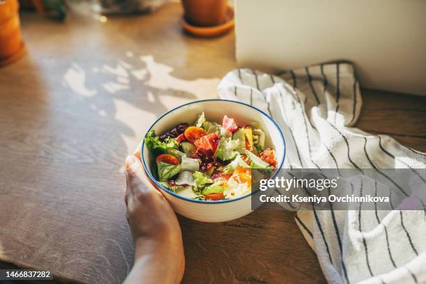 green vegan breakfast meal in bowl with spinach, arugula, avocado, seeds and sprouts. girl in leggins holding plate with hands visible, top view. clean eating, dieting, vegan food concept - woman hand crossed stockfoto's en -beelden