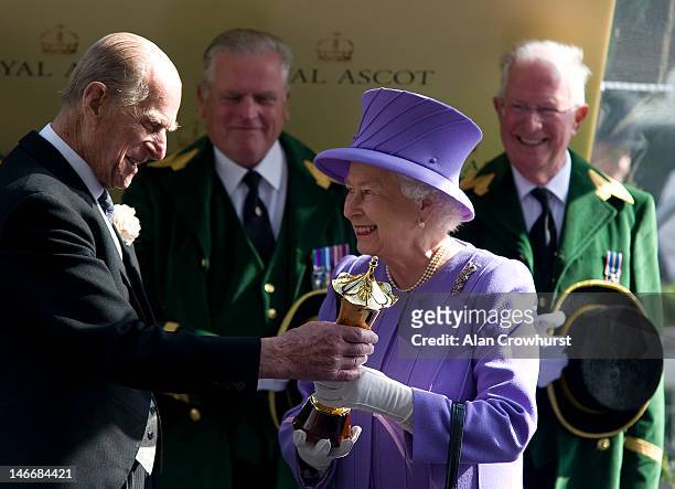 Queen Elizabeth II receives the winners trophy from Prince Philip, Duke of Edinburgh after her horse Estimate wins the Queen's Vase during Royal...