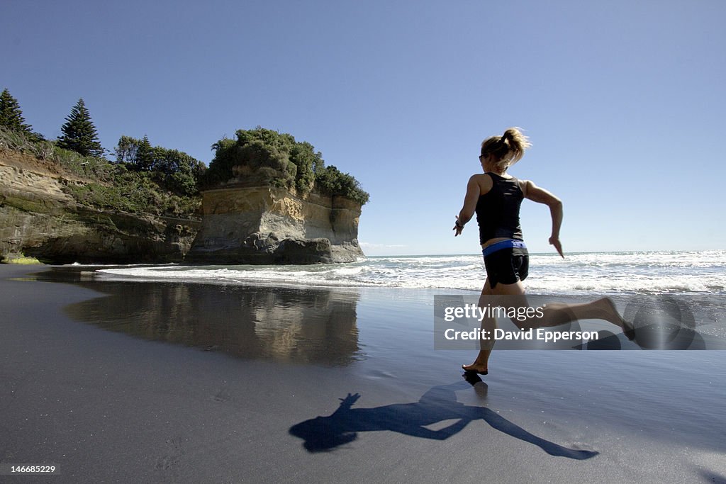 Woman running on a beach in New Zealand