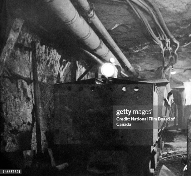 View of trolleys loaded with ore inside an underground gold mine, Val d'Or, Quebec, Canada, 1949. Photo taken during the National Film Board of...