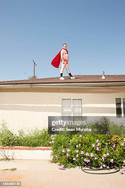 man wearing red cape and underwear on roof - cape stock-fotos und bilder