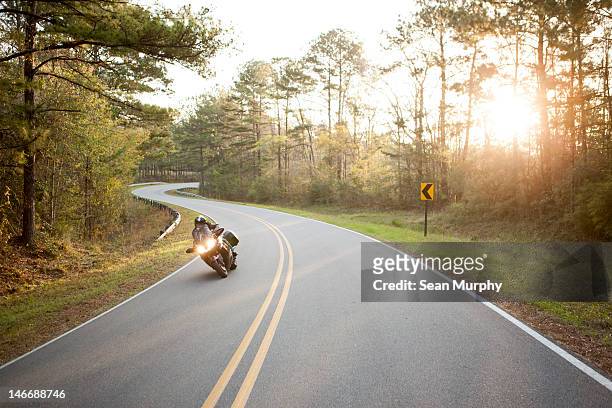 motorcycle cruising down a winding road at sunset. - casco moto blanco fotografías e imágenes de stock