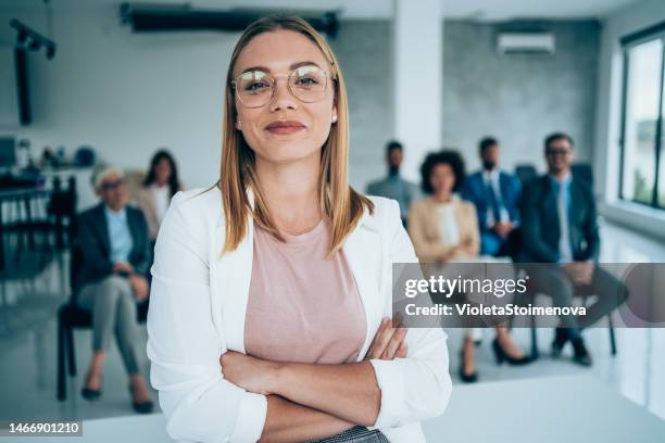 smiling public speaker in front of her colleagues in conference hall. - voor stockfoto's en -beelden