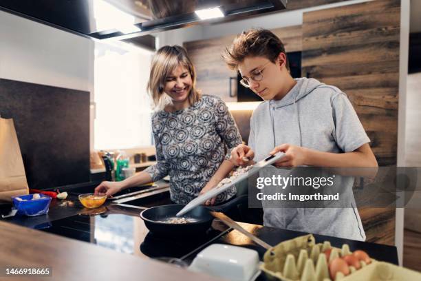 mutter und sohn bereiten gemeinsam frühstück vor - küchenhelfer stock-fotos und bilder