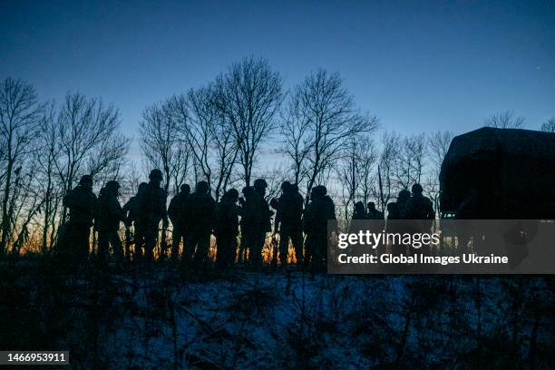 Ukrainian soldiers stand at sunset next to a vehicle on the side of a field where they dug trenches on January 10, 2023 in Donetsk Oblast, Ukraine....