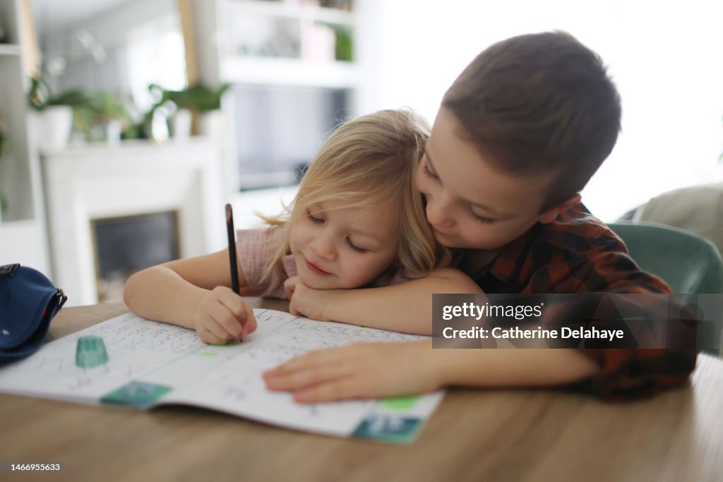 A boy helping his little sister to do homework at home