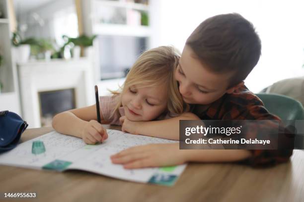 a boy helping his little sister to do homework at home - doing a favor stockfoto's en -beelden