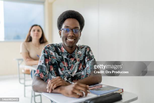 portrait of smiling young black man in college - caneta stockfoto's en -beelden